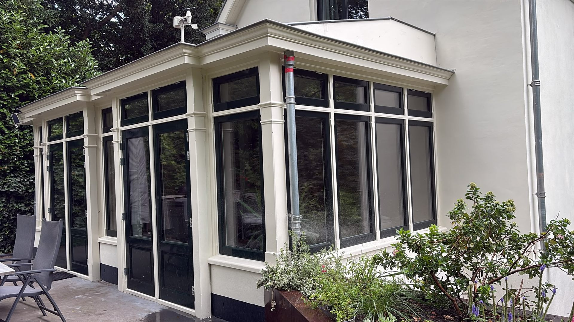 Orangerie met donkergroene houten kozijnen en crèmekleurig stijl- en regelwerk